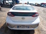 the rear end of a white car parked in a parking lot