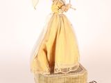 a figurine of a woman in a yellow dress holding an umbrella
