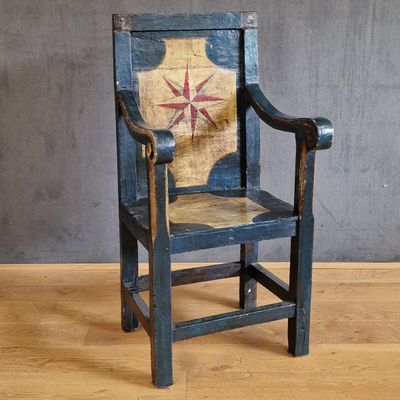 une vieille chaise en bois posée sur un parquet, près d'un mur