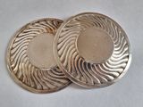two silver plated coasters sitting on top of a white surface