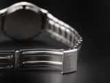 close up of a watch on a black surface with a black background