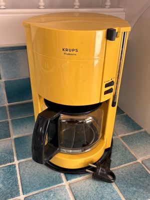 a yellow coffee maker sitting on a blue tiled floor