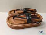 black and tan leather sandals on a white surface