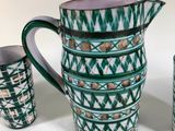 a green and white pitcher and two cups next to each other