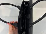 the hand is holding a black purse with a handle