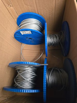 deux bobines de fil métallique dans une boîte en carton munie d'une poignée bleue