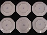 six white plates with blue designs on them sitting on a black surface