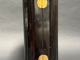 a black vase with a gold decoration on top of it