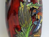 a red vase with a painting of birds on it