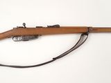 un fusil avec un canon en bois sur une surface blanche