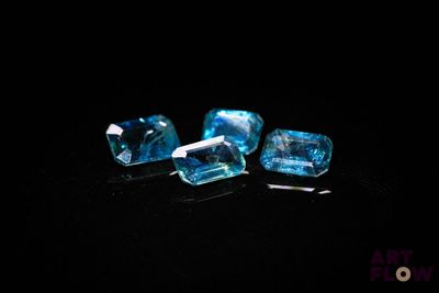 a close up of three pieces of blue topazte on a black surface
