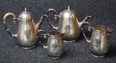 four pieces of silver tea and coffee set on a black surface