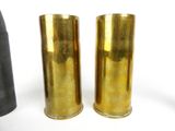 pair of brass vases on a white surface with a black vase in the background