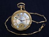 a gold pocket watch on a chain on a black background