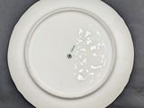 a white plate with a flower on it sitting on a table
