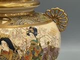 a gold vase with a picture of a woman and a man on it