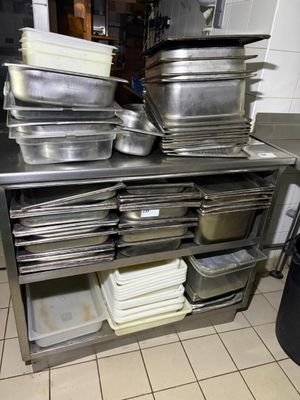 several pans are stacked on a metal shelf in a kitchen