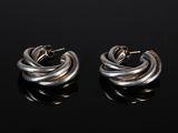 a pair of silver hoop earrings on a black surface