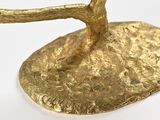 a gold sculpture of a bird on a tree branch