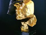 sculpture of a hand holding a piece of gold on top of a table