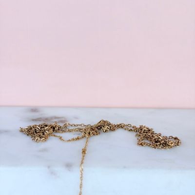 a close up of a gold necklace on a marble surface