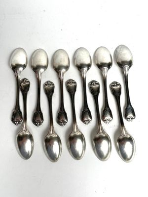 six silver spoons are lined up in a row on a white surface
