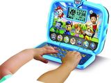a small child playing with a laptop computer on the table