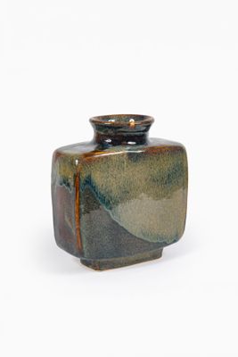 un petit vase posé sur une surface blanche