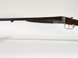 un fusil posé sur un socle transparent, devant un fond blanc