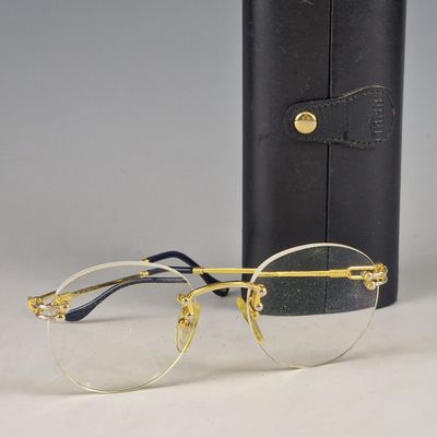 pair of gold rimmed glasses next to a black case on a table