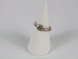 a close up of a ring on a white cone with a green stone