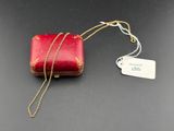 a red purse with a gold chain and a tag on it