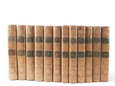 six old books lined up in rows on a white surface