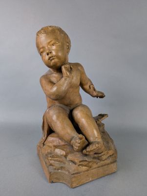 statue of a boy sitting on a rock with a bird in his hand