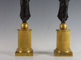 pair of bronze statues of a woman and a man on pedestals