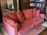 a pink couch sitting in a living room next to a book shelf