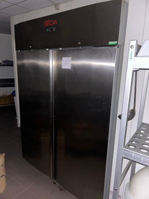 stainless steel double door refrigerator in a commercial kitchen with shelves