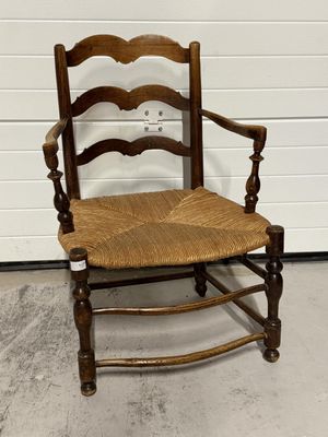 une chaise en bois avec une assise tressée et des accoudoirs