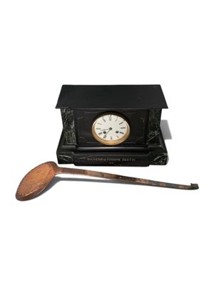 une petite horloge noire avec une cuillère en bois à côté