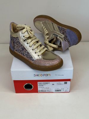 des baskets dorées et violettes à paillettes posées sur une boîte blanche