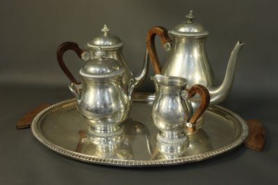 a silver tea set on a silver tray with a wooden handle