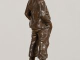 bronze statue of a boy standing on a pedestal with his hands in his pockets