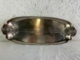 a silver plate on a table with a white wall in the background