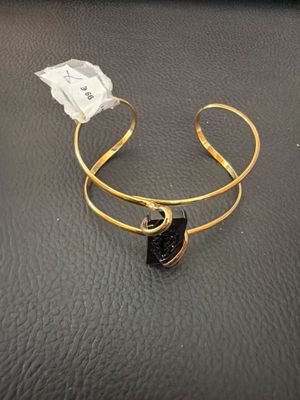 un gros plan sur un bracelet en or orné d'une pierre noire