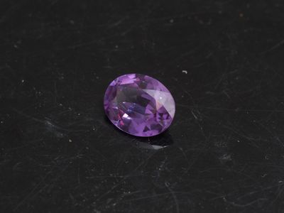 un gros plan d'une pierre précieuse violette sur une surface noire