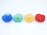quatre fleurs en plastique sont alignées les unes à côté des autres sur une surface blanche