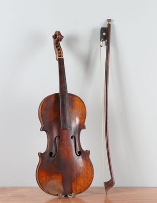 an old violin sitting on top of a wooden table next to a bow