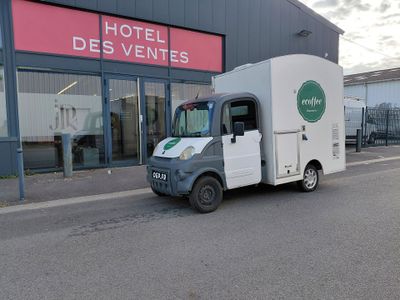 un petit camion blanc garé devant un hôtel