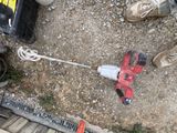 une perceuse filaire posée par terre à côté d'une paire de chaussures