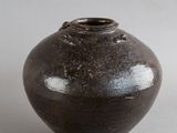 un vase noir devant lequel se trouve une petite fleur